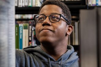 Rowan Health and Science Communication major Sedrick looks for a book in the Campbell Library.
