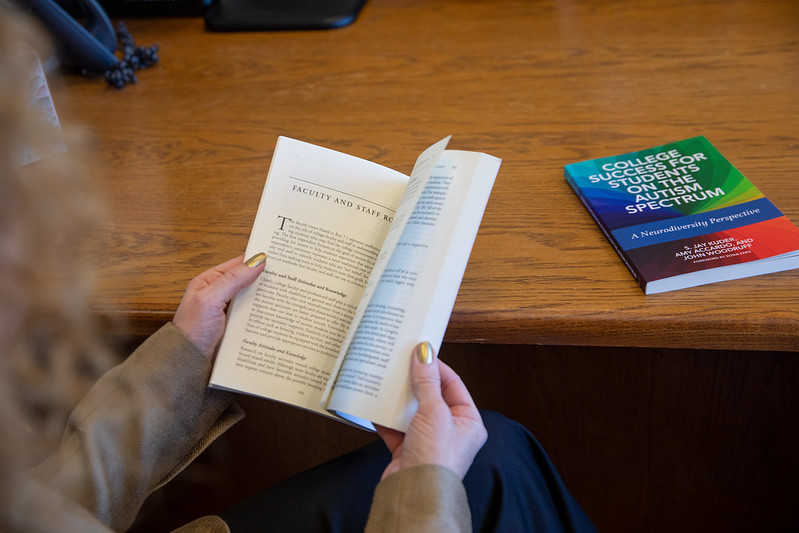 Rowan University faculty member Dr. Amy Accardo (not seen) opens the book she collaborated on with Mr. Dr. Jay Kuder and Mr. John Woodruff. 