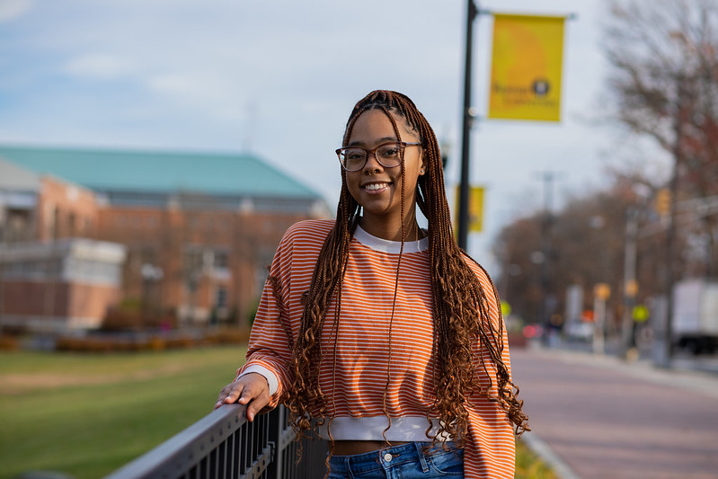 Rowan University Marketing major Lanasia poses under a Rowan banner.