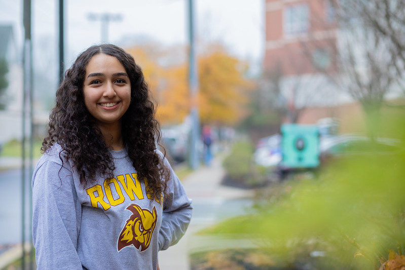 Biomedical Engineering major Miral smiles outside wearing a Rowan shirt.