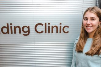 Rowan College of Education student Isabella stands next to the Reading Clinic room inside James Hall.