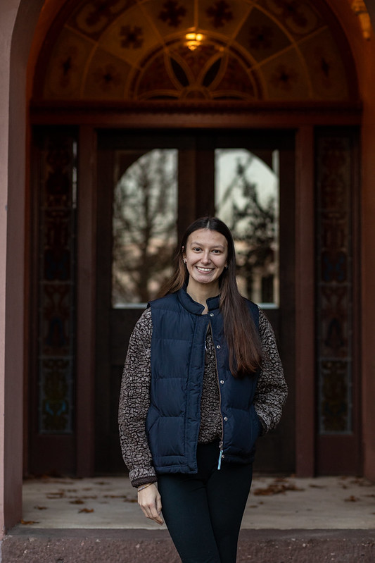 Rowan University Law and Justice major Kayla stands in front of a double doorway on campus.