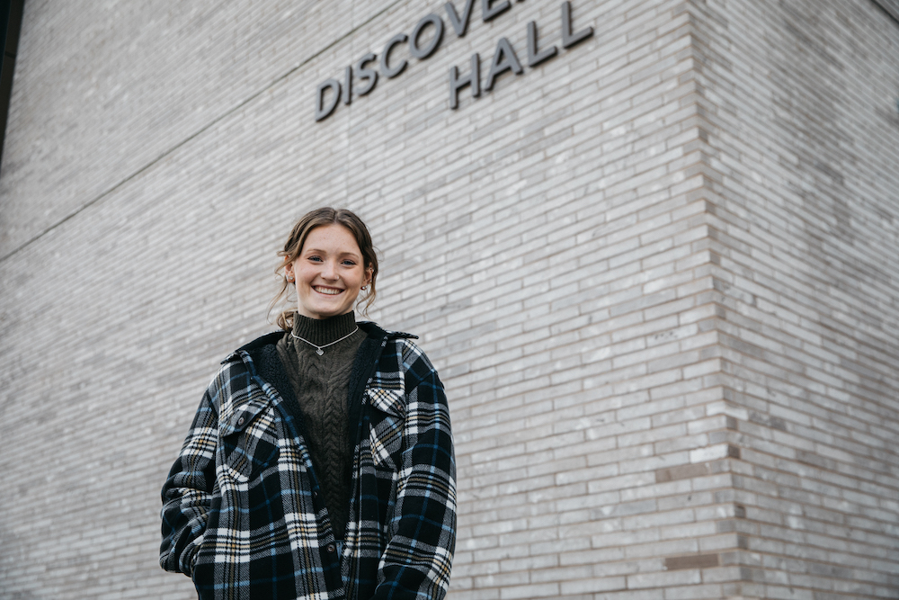 Rowan University Molecular and Cellular Biology major Lauren smiles outside the Discovery Hall building on campus.