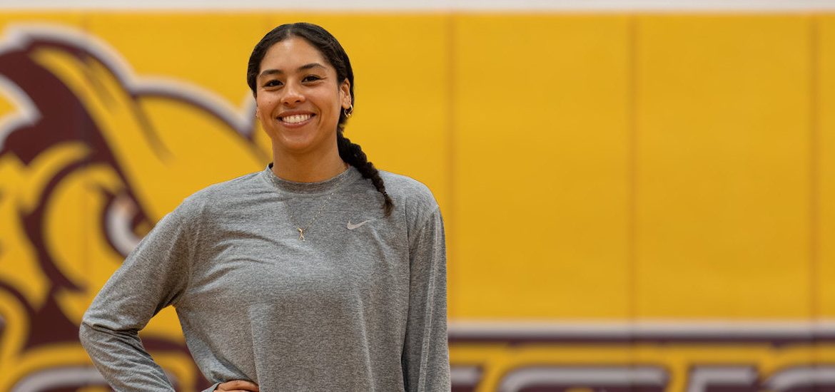 Rowan University Health and Physical Education major Adrianna is standing out front of the PROF logo in her basketball gear.