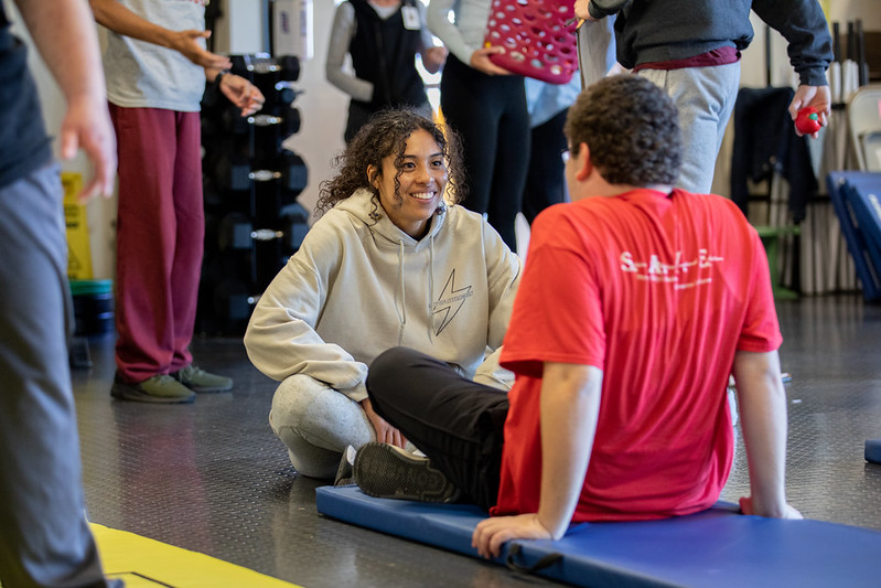 Rowan University Health and Physical Education major Adrianna can be seen helping a student out with stretching. 