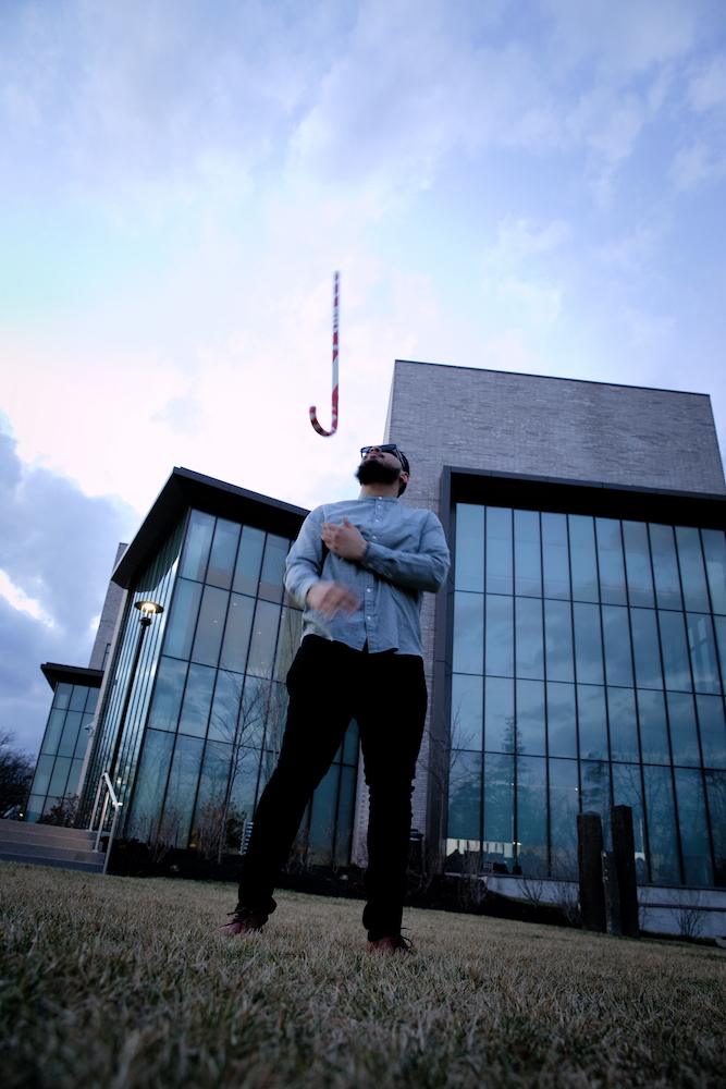 Biological Sciences major Fadi Khan stands with his cane in the air outside Discovery Hall.