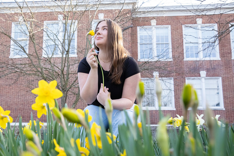 Abigail Cassino sniffs a daffodil in a field. 