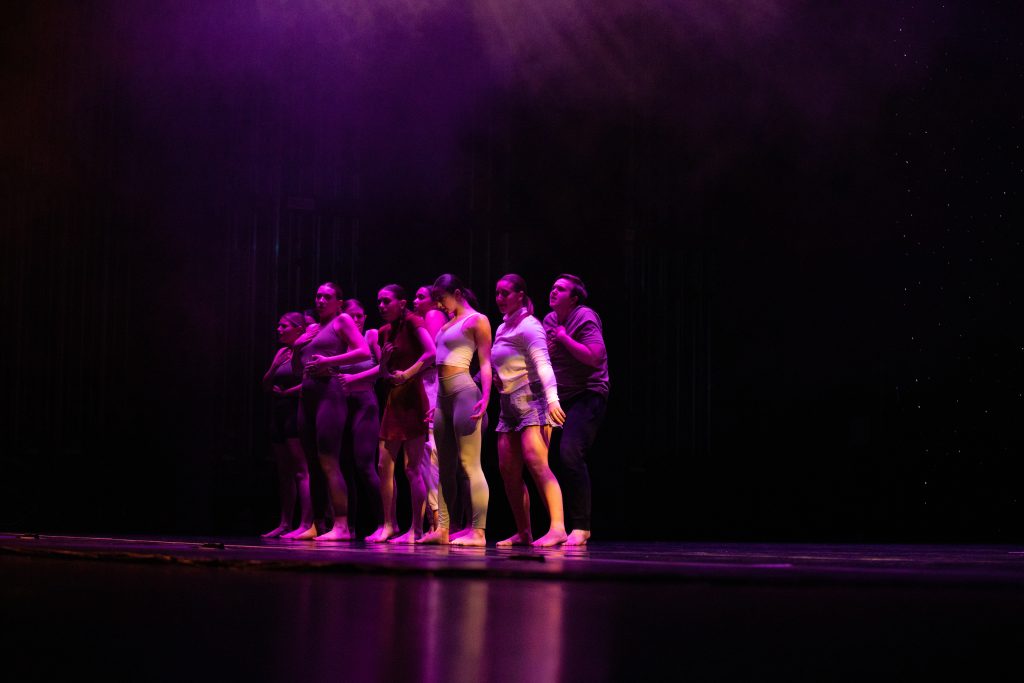 The dance extensions team stands in a dance pose on stage. 