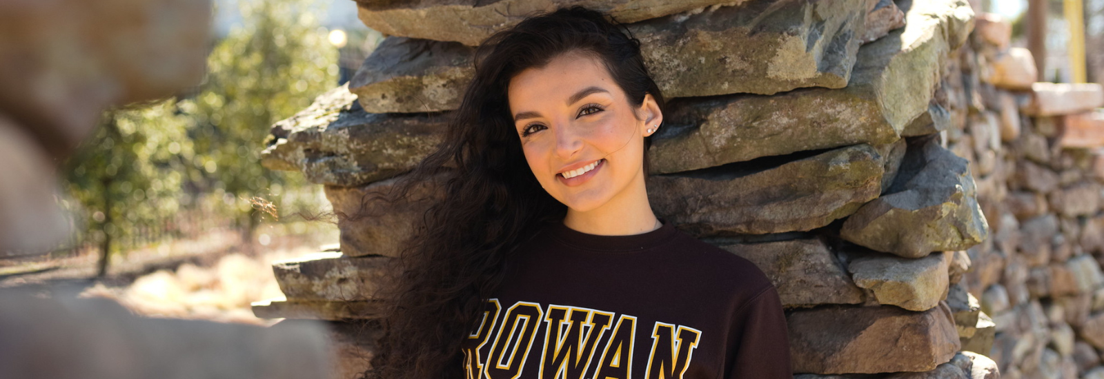 Rowan University Psychology major Siena stands underneath the art installation Time Sweeps by Discovery Hall.
