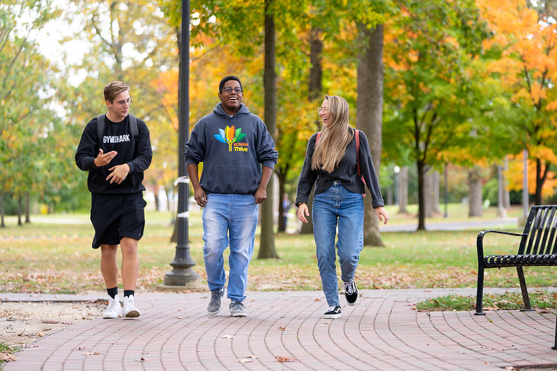 Sedrick is with friends and is walking around on campus. 