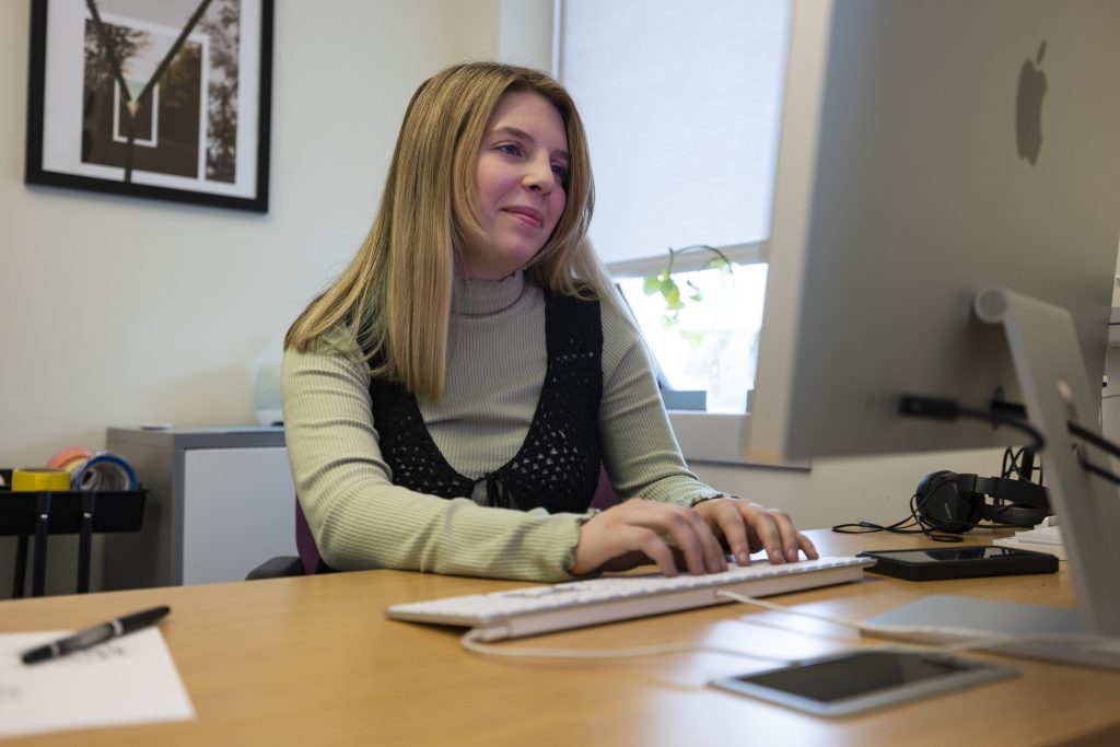 Isabella Shainline is sitting at a desk typing on a computer.