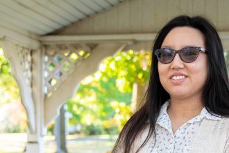 Suzie is standing in a pavilion and smiling at the camera.