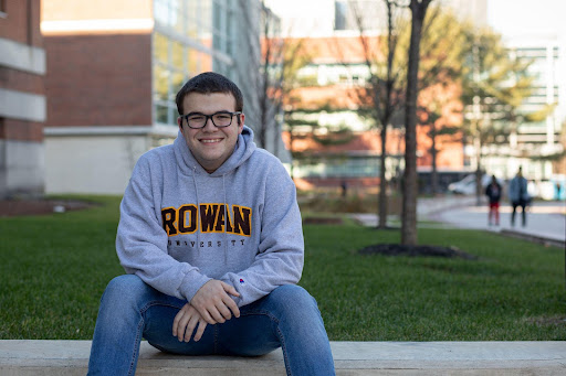 Connor Bicknell, in a Rowan sweatshirt, sitting and smiling at the camera.
