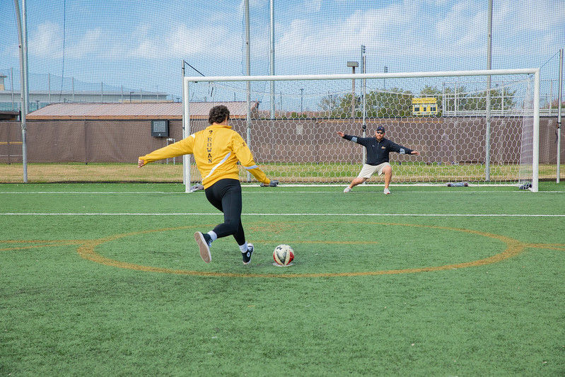 Miranda is shooting a soccer ball into a net.