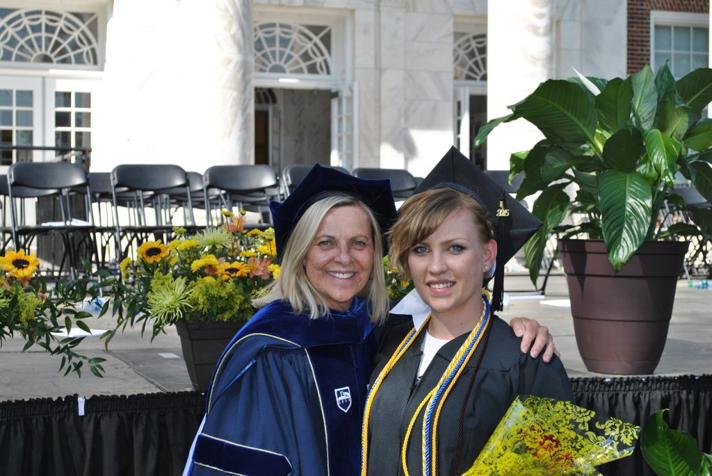 Kate with her aunt, Dr. Louise Karwowski, both in graduation regalia with Kate holding flowers. 