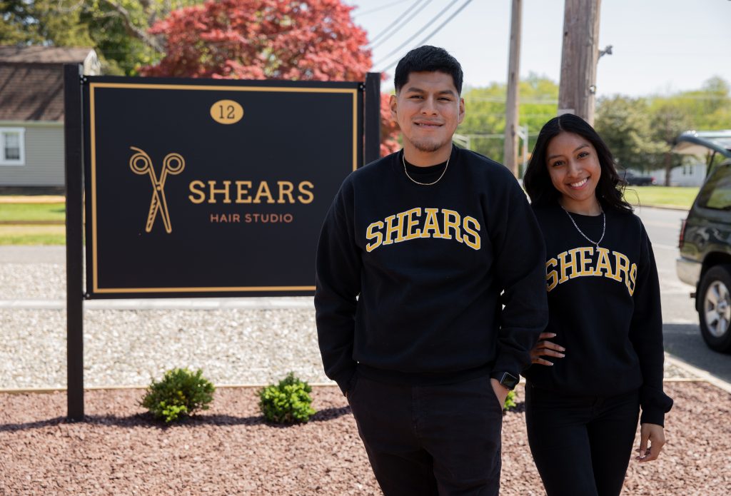 Julian and Elizabeth posing outside, in front of the Shears Hair Studio sign.