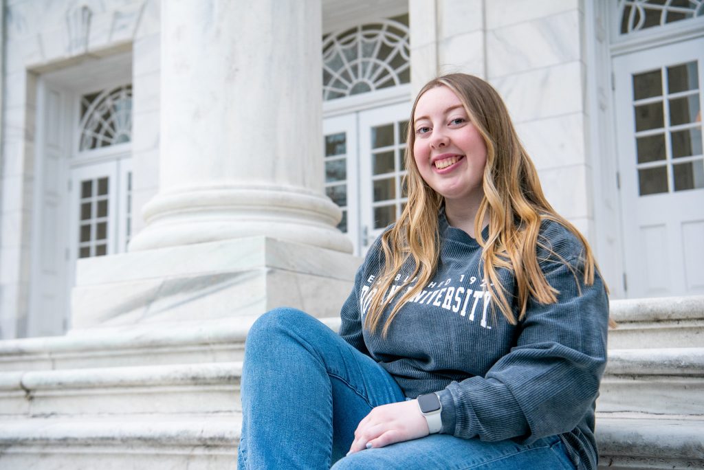 Paige sits on Bunce Hall's marble steps. 