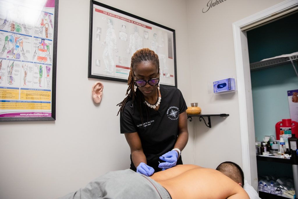 Chaliyah performs acupuncture on a patient's back.