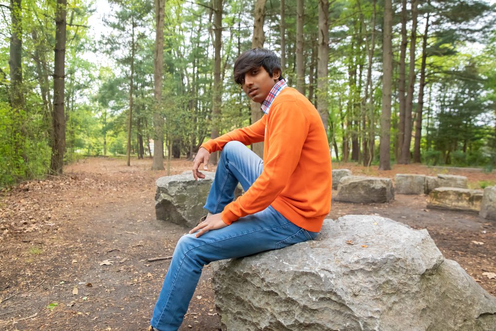 Kriish leaning up against a rock outside