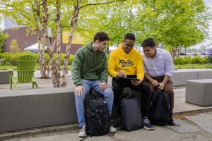 Osvaldo and his friends look at something on a tablet while sitting together outside.