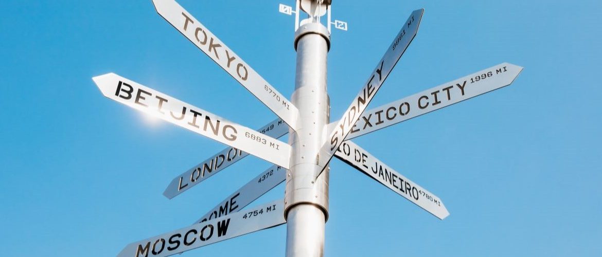 A street sign with many different countries on it.