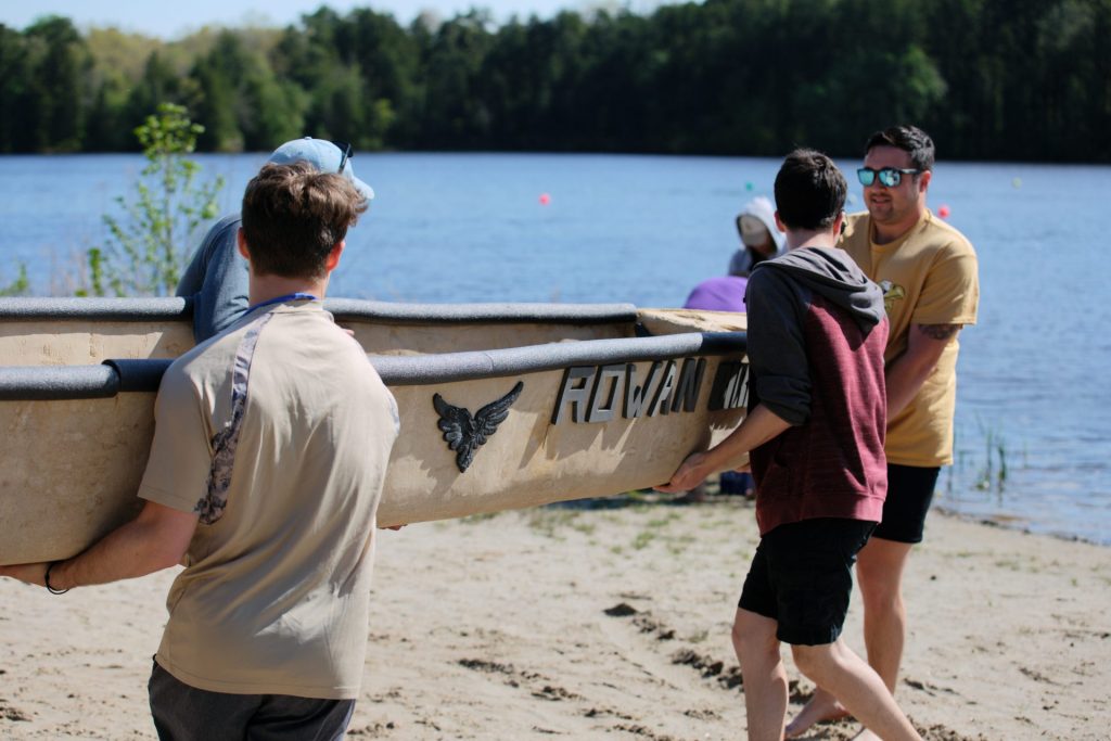 Students carry the concrete canoe to the water. 