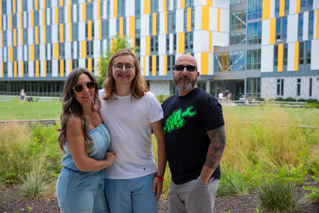 A student and their family standing outside of Holly Pointe Commons.
