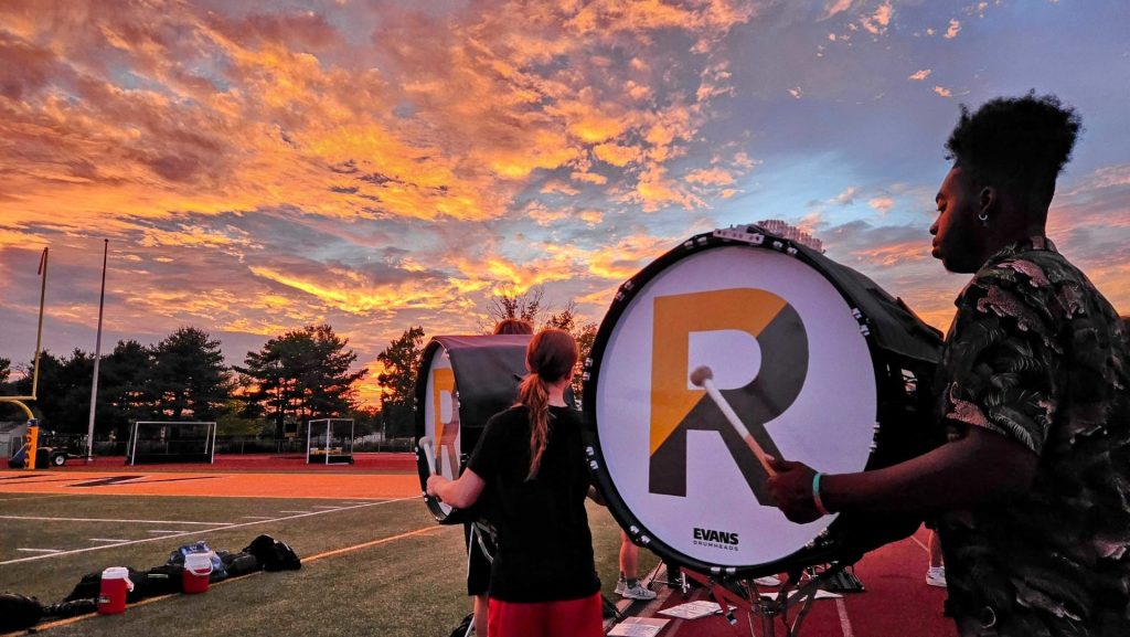 Rowan University marching band with a dramatic sunset behind the drum.