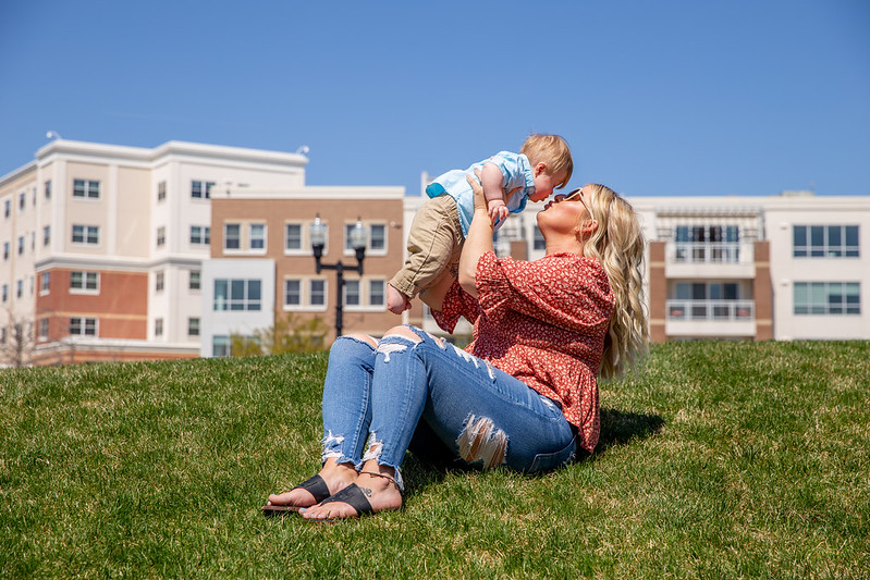 A Rowan University student holds her baby up in the air to kiss his face on campus. 