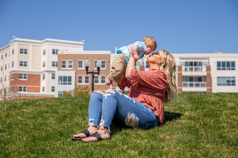 A Rowan University student holds her baby up in the air to kiss his face on campus.