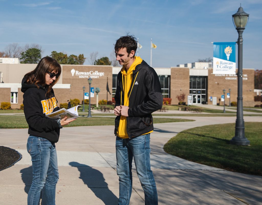 Two Rowan University students look at a catalog on the community college campus. 