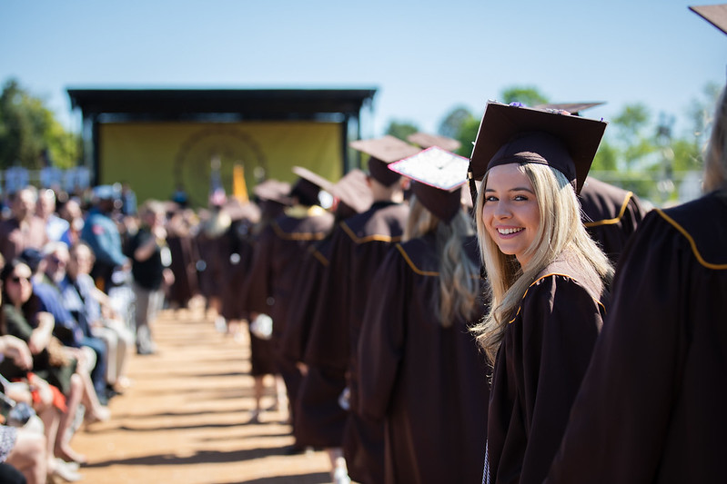 A girl looks backward at the camera during a graduation ceremony at Rowan University while everyone else looks forward. 