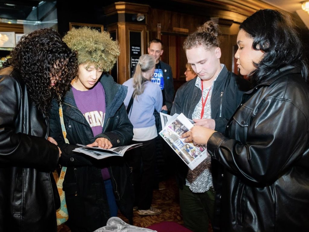 Adam and three crew members look through the program at a film festival.