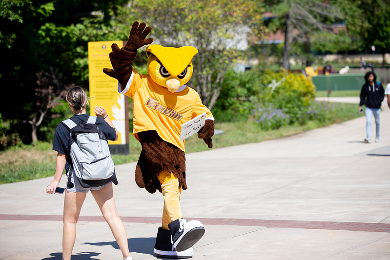 The school mascot giving a high five to a student. 