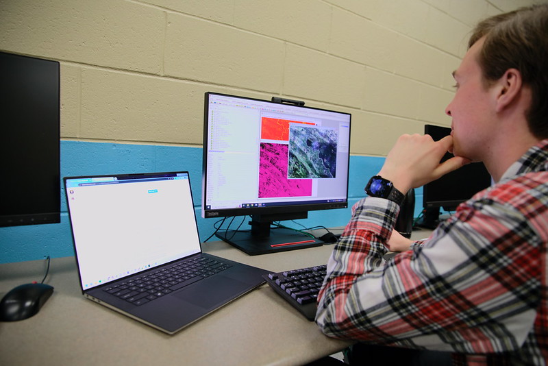 A student works on two monitors for a GIS project. 