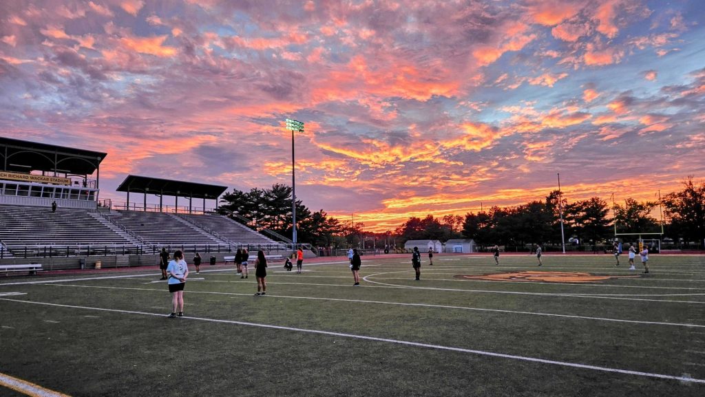 A dramatic pink-blue-orange-purple sunset over the athletic field. 