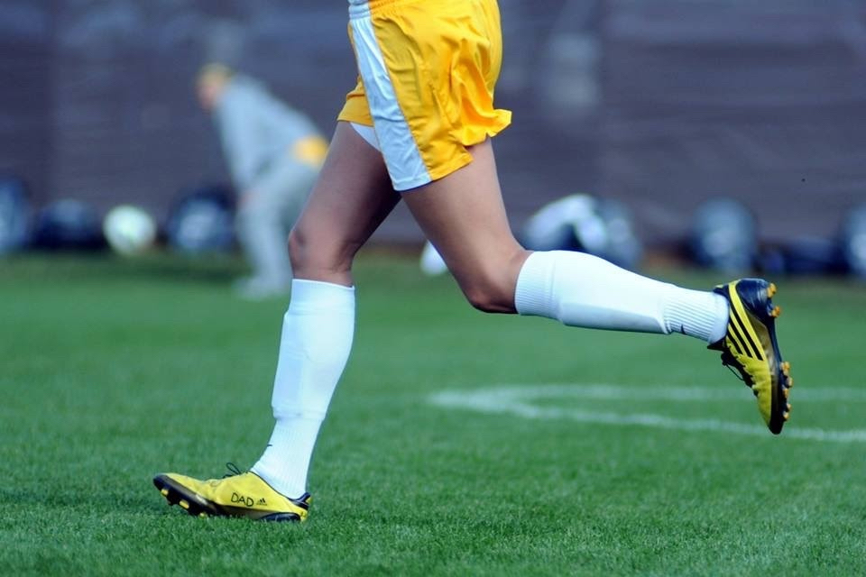 A close up of Miranda's soccer cleats with "Dad" written in memory of her father. 