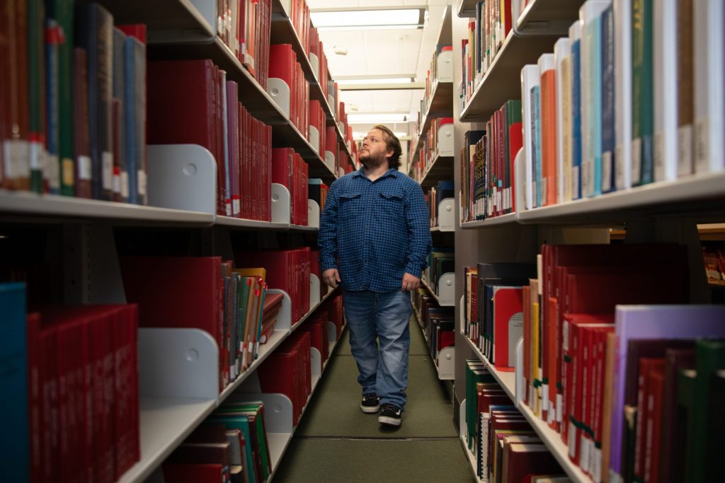 Nicholas walks through the aisles of books at the library. 