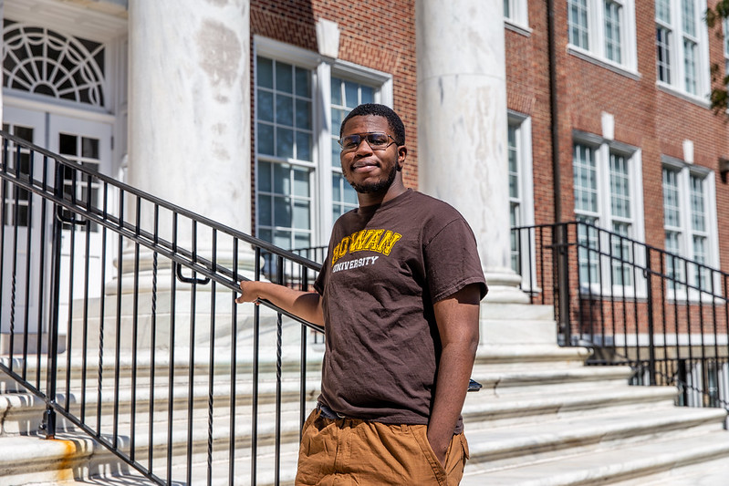 Alex stands at the bottom of the marble steps in front of Bunce Hall. 