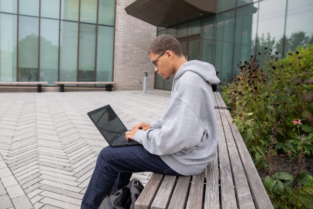 Steven Warner sitting outside of Discovery Hall with his laptop.