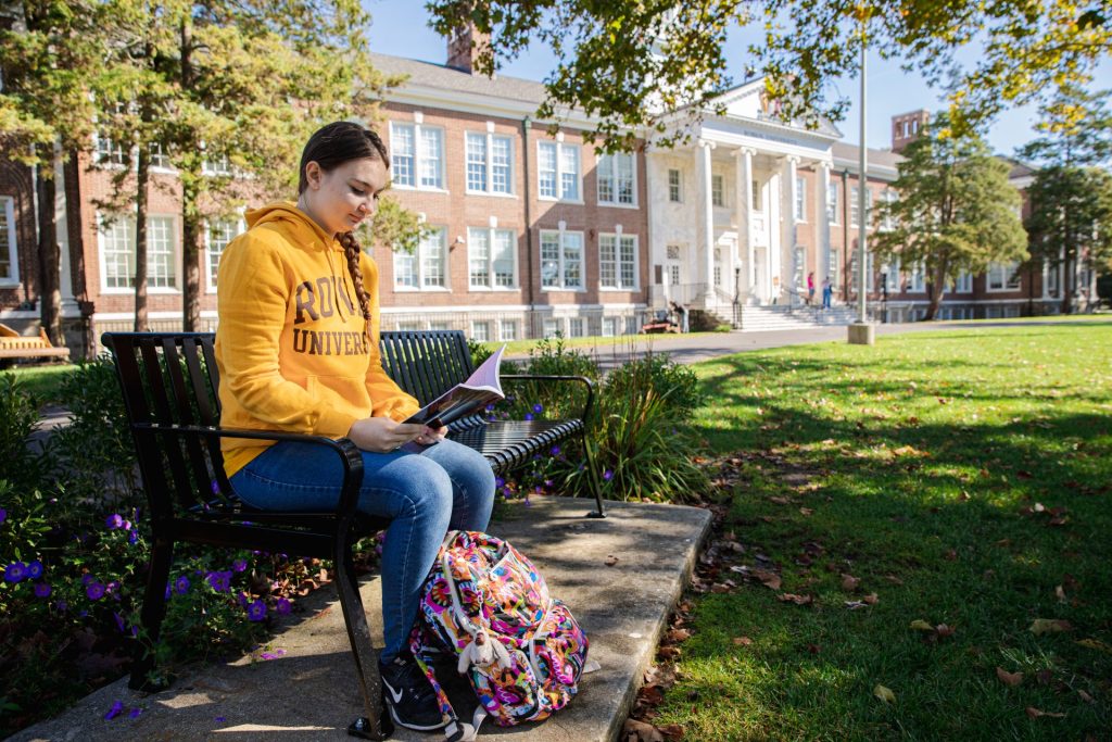 A female student today studies on a bench in front of Bunce Hall. 