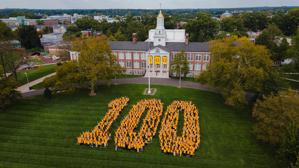 Rowan community members create a human sign spelling out the digits 100 to celebrate Rowan's centennial. 