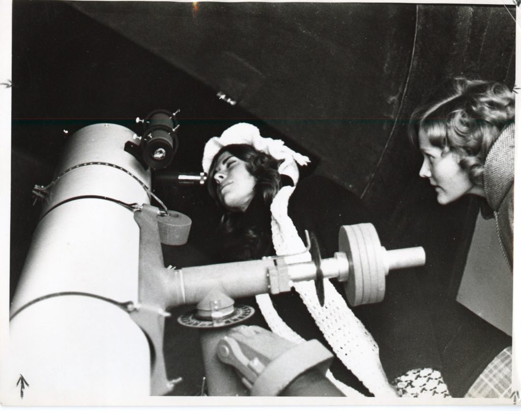 Two students peer through a telescope, perhaps in the early 1980s. 