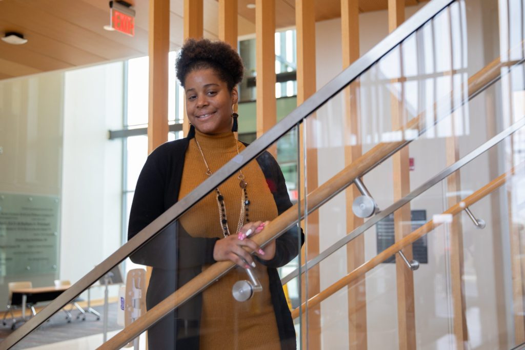 NyEsha standing on the lobby staircase inside of the Rohrer College of Business.