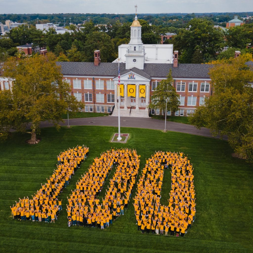 A drone view of the digits of 100 illustrated on Bunce Green by people wearing matching yellow Rowan shirts to celebrate the centennial in front of Bunce Hall. 